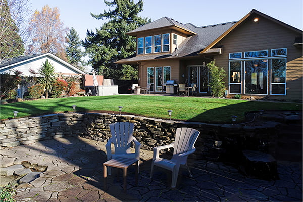 Two Adirondack chairs in the back yard of home listing